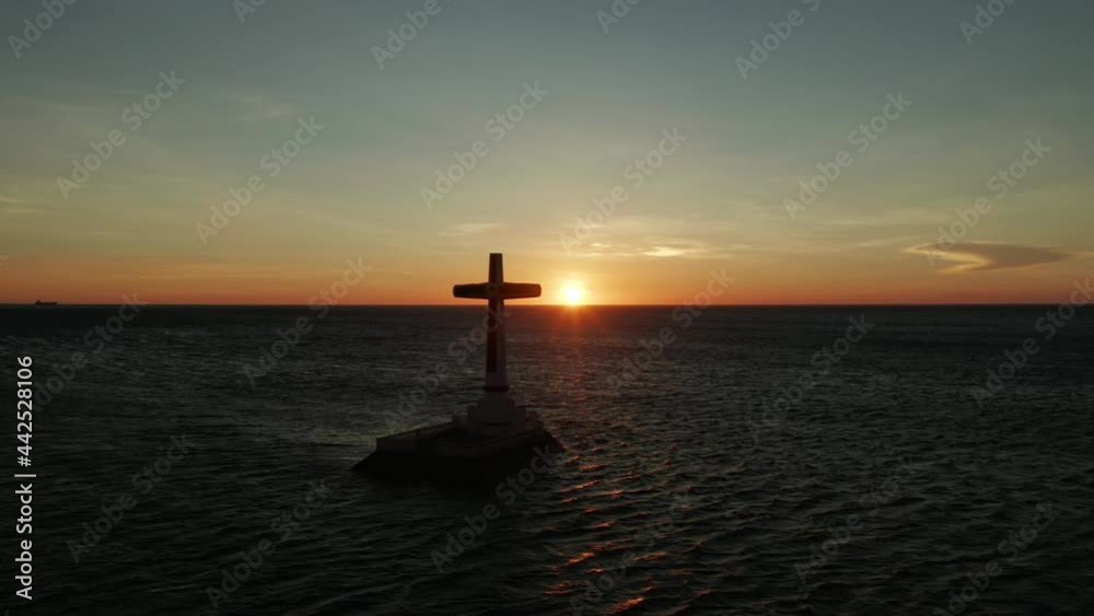 Colorful bright clouds during sunset over the sea. Catholic cross in sunken cemetery in the sea at sunset, aerial drone. colorful sky during the sunset. Large crucafix marking the underwater sunken Colorful bright clouds during sunset over the sea. Catholic cross in sunken cemetery in the sea at sunset, aerial drone. colorful sky during the sunset. Large crucafix marking the underwater sunken