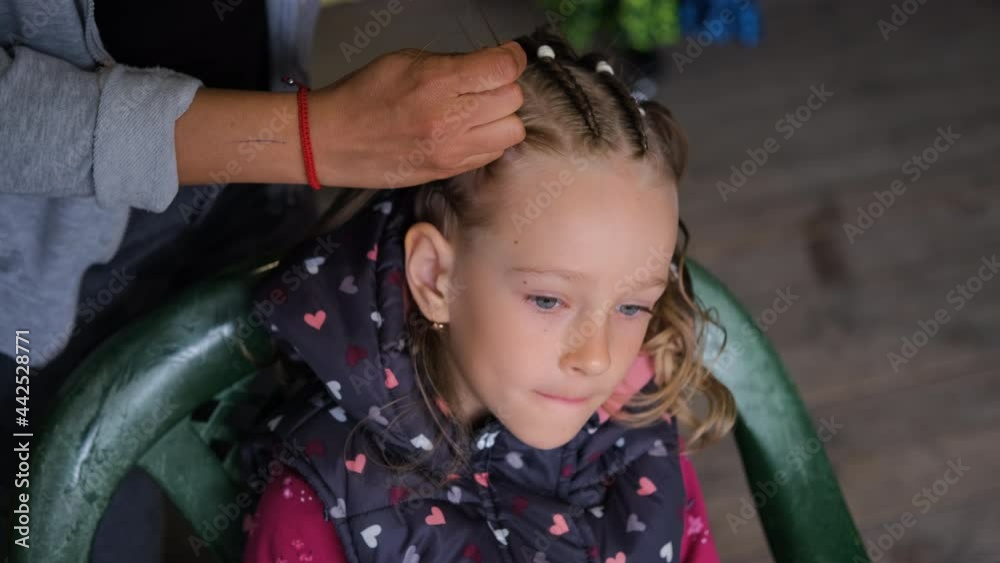 Hands of Female Hair Stylist Braiding Hair of Little Girl, Creating Afro Pigtails Braids with Multi-Colored Threads and Dreadlocks Hands of Female Hair Stylist Braiding Hair of Little Girl, Creating Afro Pigtails Braids with Multi-Colored Threads and Dreadlocks