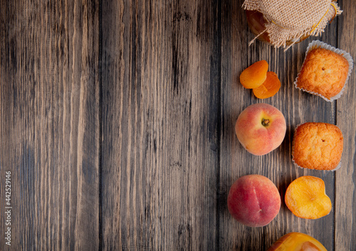 top view of fresh ripe peaches with muffins and peach jam in a glass jar on rustic wooden background with copy space