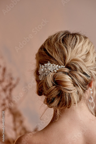 A classic wedding bun. The bride's hair, hairdressing. Blonde with curly hair.