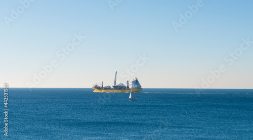 Large Ship Out In The Mediterranean Sea With A Sailboat In Front  Genoa, Liguria, Italy. © Mats Silvan