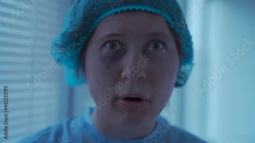 Crazy woman patient of neuropsychiatric clinic in medical clothes, has problems with perception of reality, mental woman lags behind in development and looks somewhere interested and then gets scared.