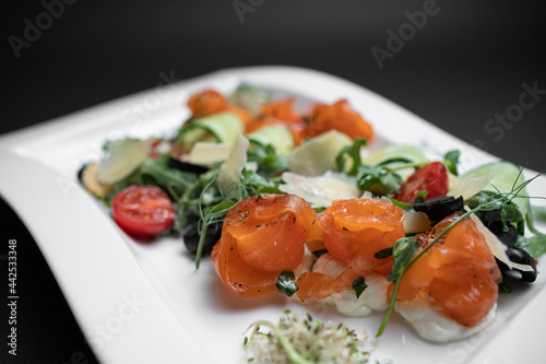 closeup of salad with lightly salted salmon and vegetables on black background