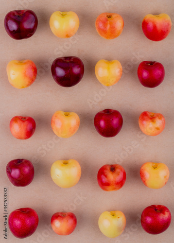 top view of red ripe cherries and rainier cherries isolated on brow paper texture background