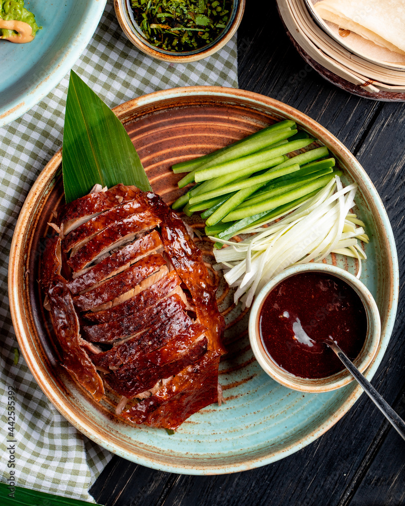 Фотография top view of traditional asian food peking duck with cucumbers and sauce on a pla