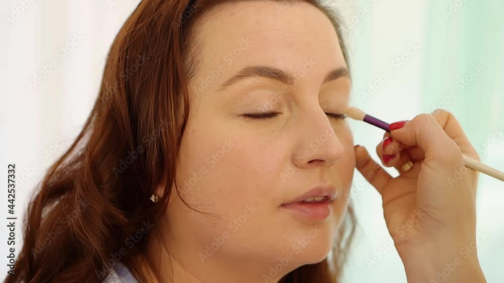 women do make-up, paint the eyelids on the eyes with a makeup brush. women do make-up, paint the eyelids on the eyes with a makeup brush.
