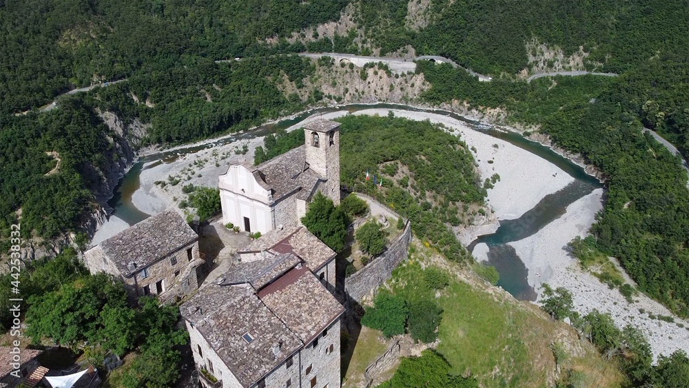 Europe, Italy, Val Trebbia, Brugnello is an ancient historical village above the mountain overlooking the incredible river that reaches Bobbio - drone view of  San Salvatore  , the bends of the river