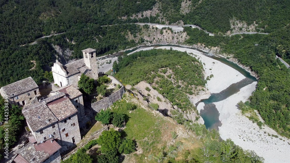 Europe, Italy, Val Trebbia, Brugnello is an ancient historical village above the mountain overlooking the incredible river that reaches Bobbio - drone view of San Salvatore , the bends of the river