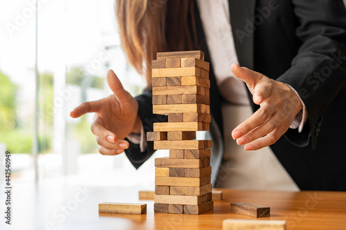 businesswoman holds her hand on a wooden block with a weak base. It is like a business risk mitigation strategy. and project management the best of the business