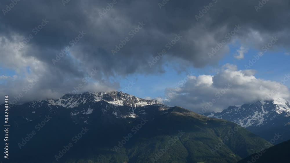 Time lapse on the mountains of Val Venosta, Northern Italy. A storm is brewing: ominous black clouds are covering the blue sky. Concept of weather variability and bad weather. Time lapse on the mountains of Val Venosta, Northern Italy. A storm is brewing: ominous black clouds are covering the blue sky. Concept of weather variability and bad weather.