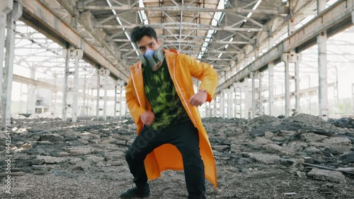 Young male dancer in protective mask dancing in ruined abandoned building