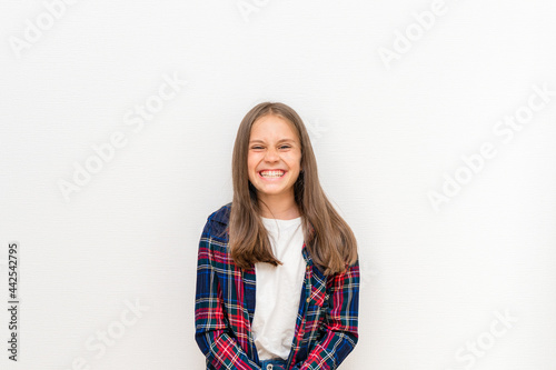 Portrait of a laughing little girl with long blonde hair on a white background