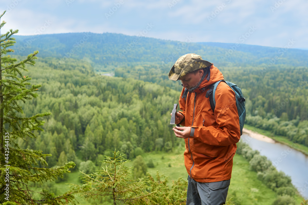 man geologist on an expedition examines a stone for hardness with a hammer