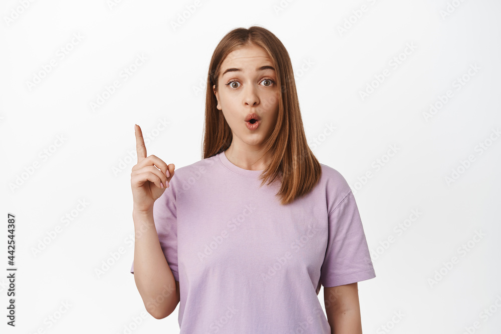 Got excellent idea. Excited blond girl says suggestion, pointing up and gasp thrilled, showing announcement, event advertisement or store banner, standing over white background