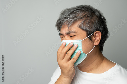 Sick Asian man wearing a medical face mask and Coughing and covering his mouth with my hand. Concept of protection pandemic coronavirus and respiratory disease