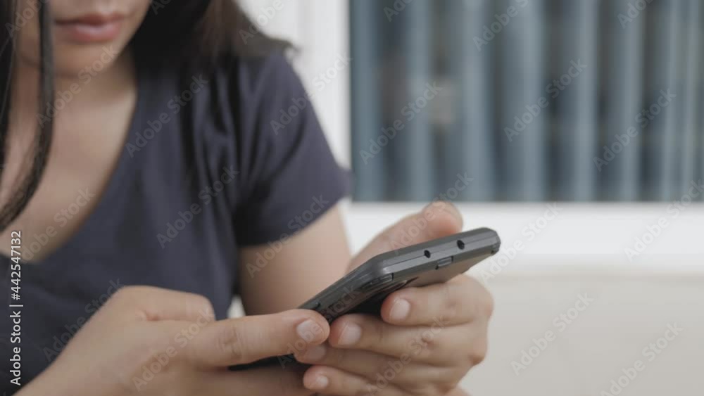 An Asian woman with a serious expression while touching a mobile phone screen.