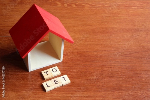 Foto Miniature house and wooden cube with text TO LET