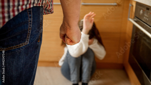 Angry father threats and beating his crying daughter with fist. Concept of domestic violence, parent abuse and family aggression.