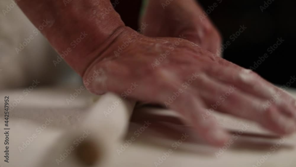 Hand rolling dough to make stuffed Chinese gyoza dumplings - isolated on hands and rolling pin