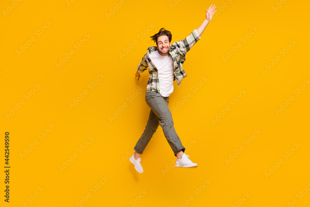 Full size profile side photo of young man happy positive smile have fun jump go walk step isolated over yellow color background Full size profile side photo of young man happy positive smile have fun jump go walk step isolated over yellow color background