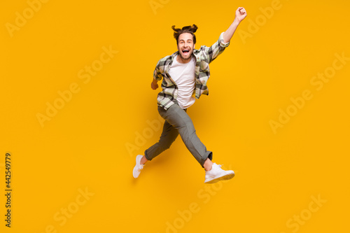 Full body photo of energetic young happy man jump up run empty space smile isolated on yellow color background