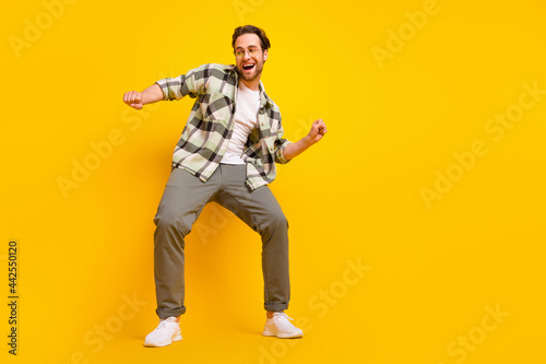 Full body photo of young cheerful man happy positive smile dance music clubber isolated over yellow color background
