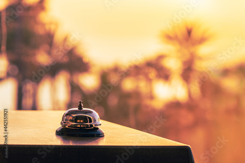 Beach hotel service bell against the background of coastline sea and palm tree on sunset. Travel concept. 24-hour hotel front desk. Late check-out.