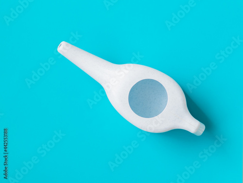 Neti pot for nasal rinsing on a blue background,  sinus rinse, health, treatment for congestion.