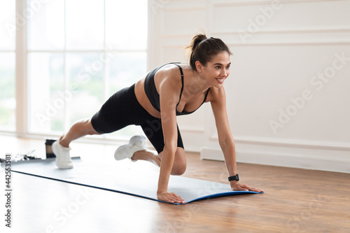 Young Cheerful Woman Doing Cross Body Mountain Climbers Exercise