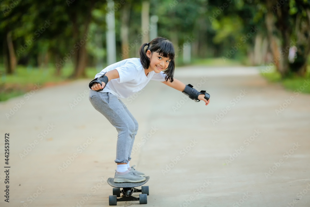 Cute little girl asia playing skateboard or surf skate in the skate park. Which increases the development and enhances learning skills, sport activity lifestyle concept, Healthy and exercise. Cute little girl asia playing skateboard or surf skate in the skate park. Which increases the development and enhances learning skills, sport activity lifestyle concept, Healthy and exercise.