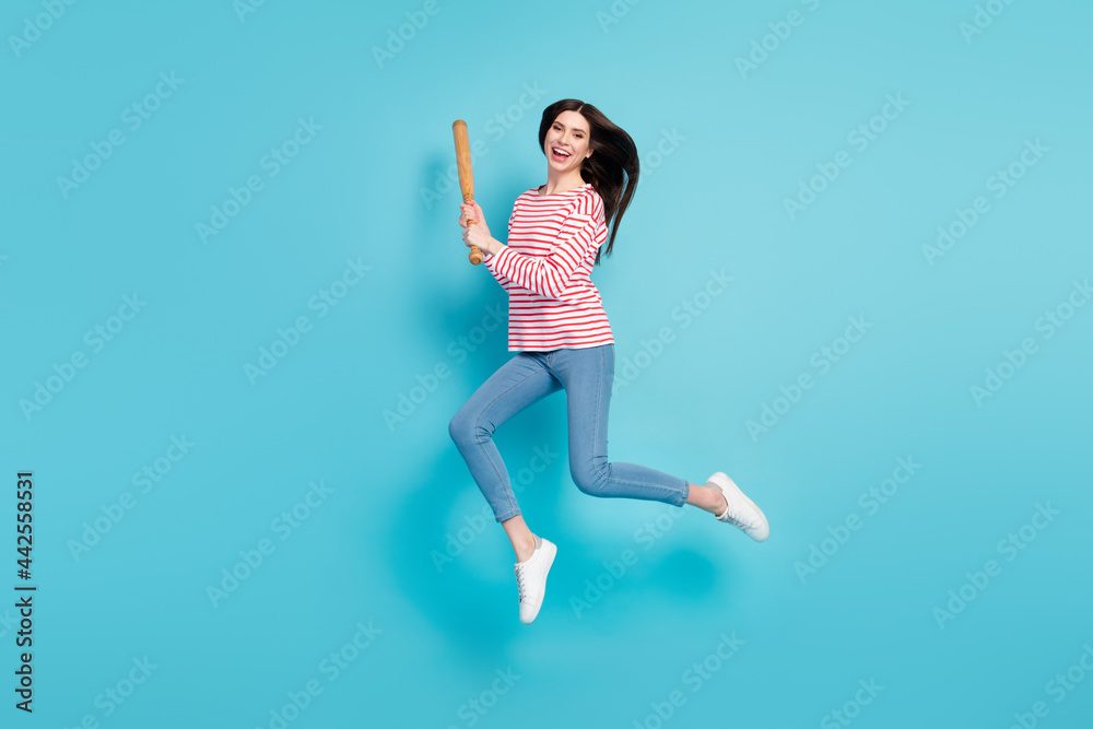 Full length body size view of attractive cheery girl jumping having fun fighting bat isolated over bright blue color background Full length body size view of attractive cheery girl jumping having fun fighting bat isolated over bright blue color background