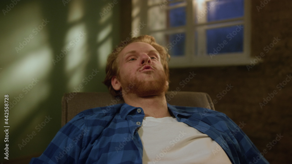 Joyful man relaxing in new apartment. Smiling guy falling into armchair. Joyful man relaxing in new apartment. Smiling guy falling into armchair.