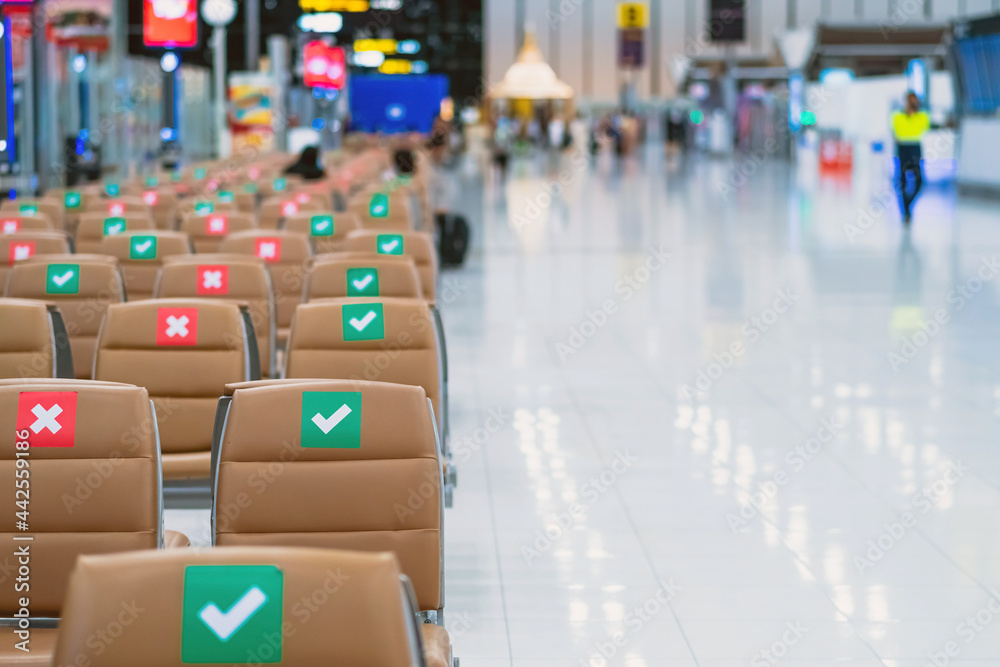 Obraz premium Rows empty brown chairs with the sticker sign sitting position for social distancing in waiting terminal of the airport to prevent of Corona virus (Covid-19). Safe travel new normal social distancing.