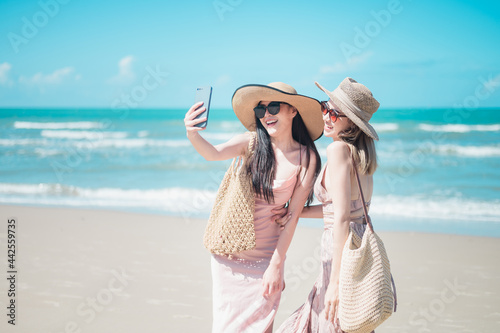 Two Asian girls are relaxing, taking pictures, playing on the beach. © 2B