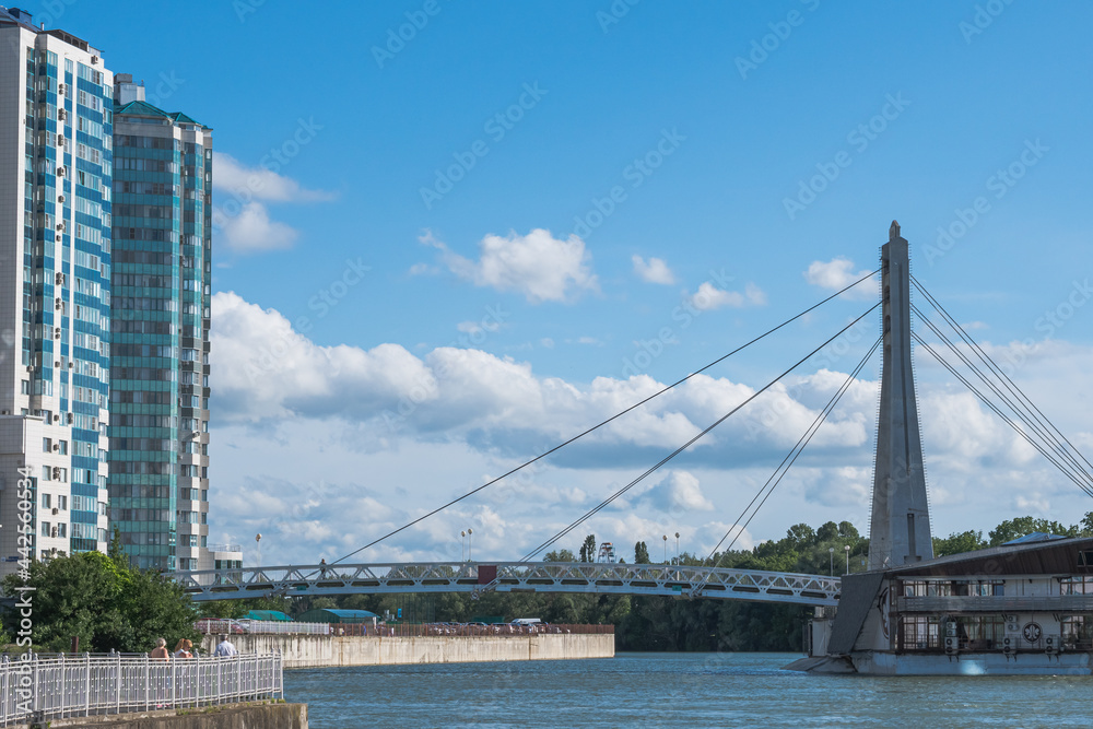 Fototapeta premium Cable-stayed bridge over the Kuban River and a multi-storey house on the embankment. Urban landscape