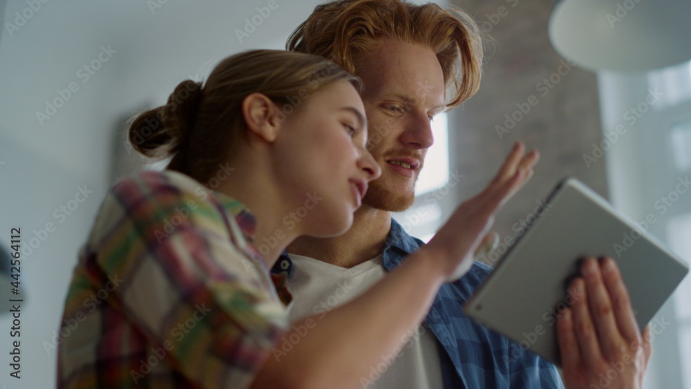 Smiling couple with tablet moving hands during house renovation indoors.