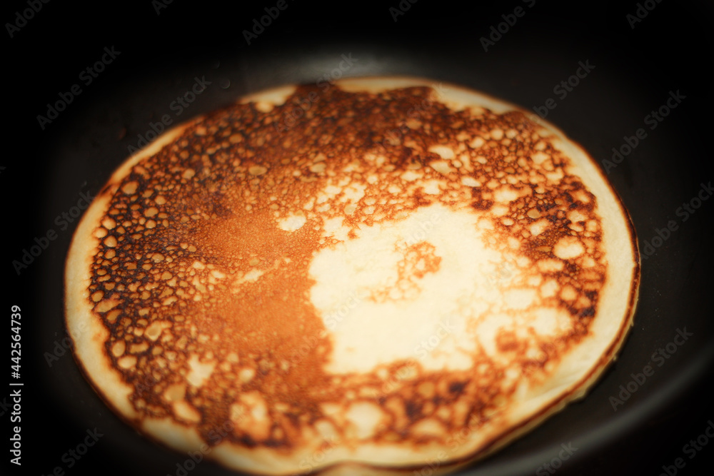 Pancake is fried in a pan. Rosy hot sweet breakfast.