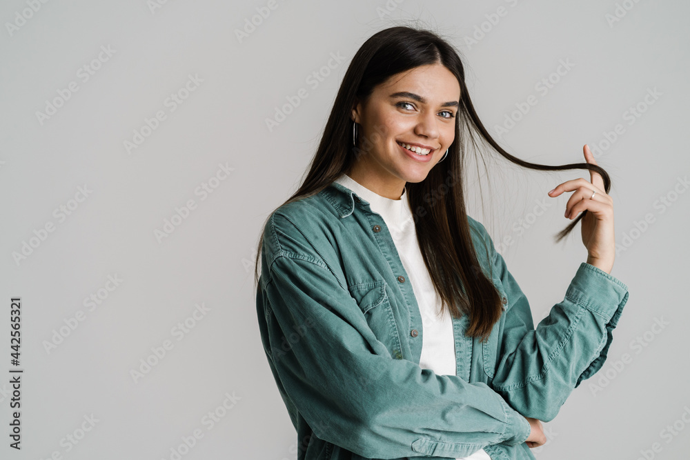 Young brunette woman smiling and holding lock of her hair Young brunette woman smiling and holding lock of her hair
