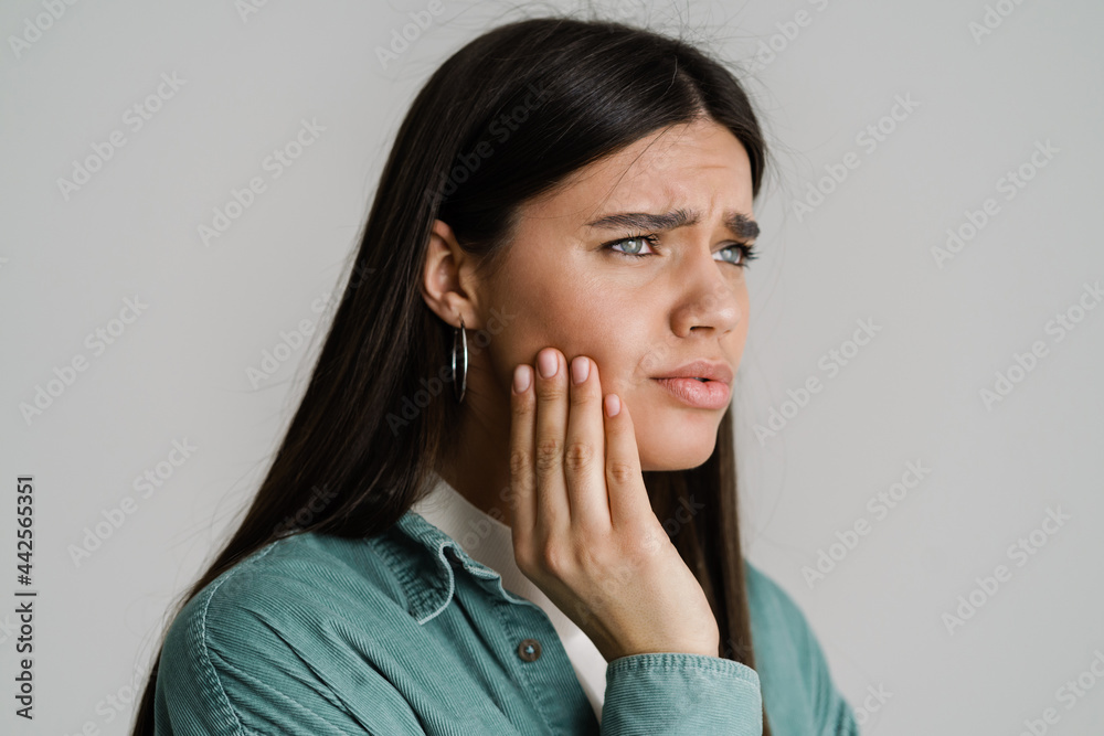 Young unhappy woman with toothache rubbing her cheek Young unhappy woman with toothache rubbing her cheek