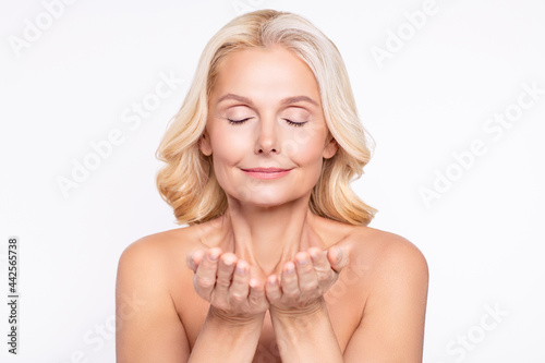 Portrait of attractive dreamy healthy grey-haired woman washing clear skin exfoliating scrub isolated over white color background
