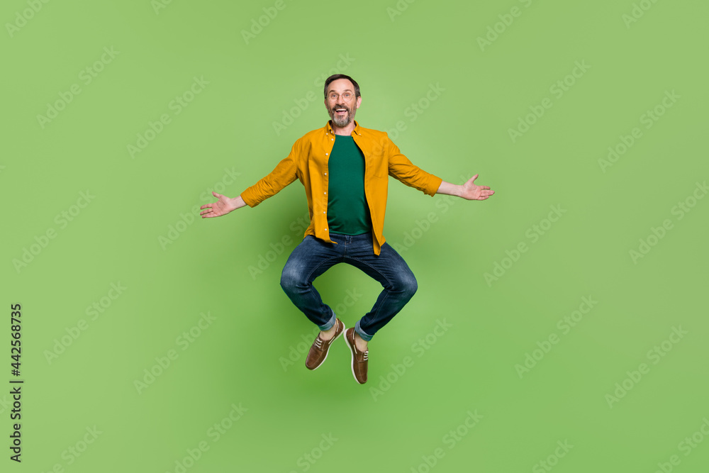 Full body photo of cheerful mature man happy positive smile have fun jump isolated over green color background