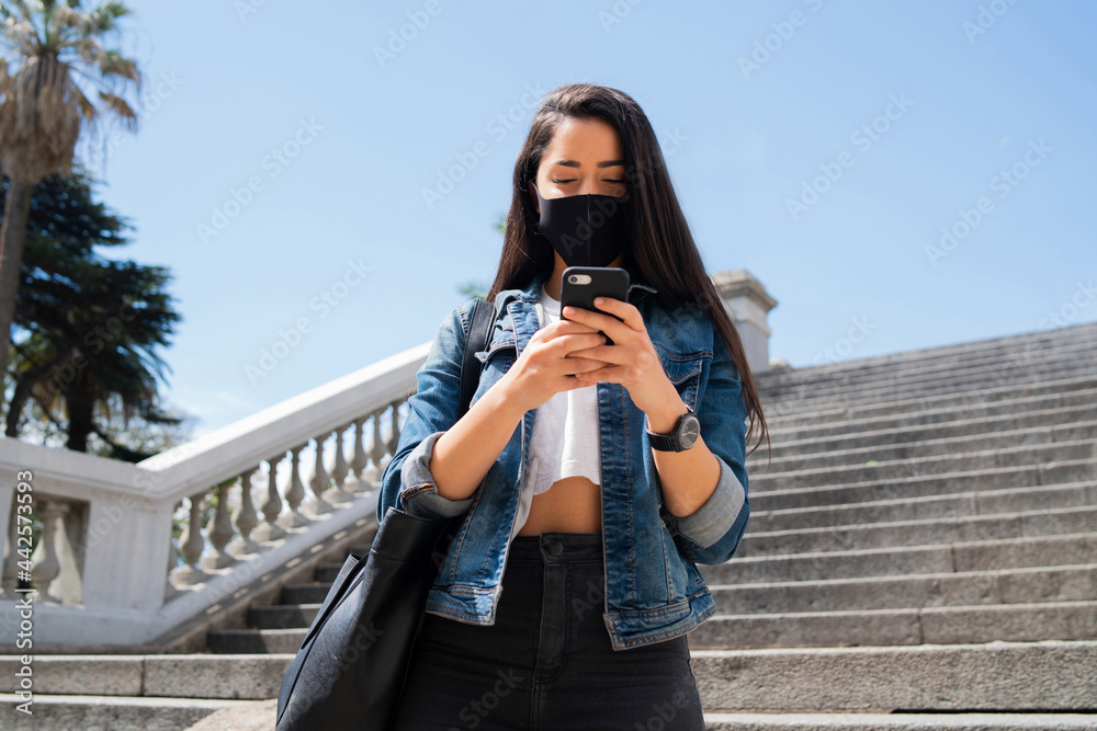 Young woman using her mobile phone outdoors.