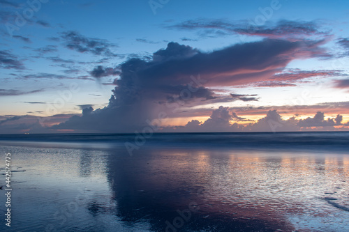 Beautiful sunrise at the beach with pretty clouds and blue sky © chris