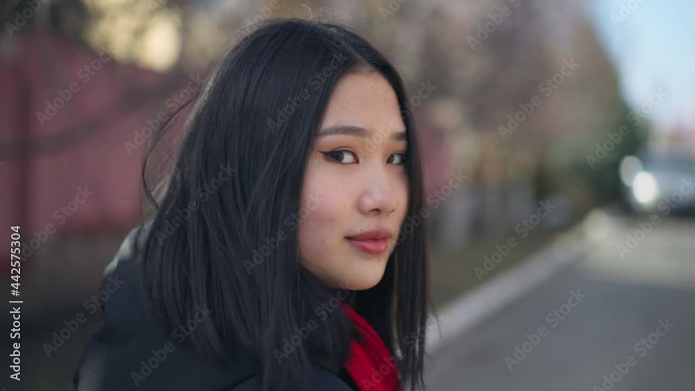 Young woman turning to camera smiling standing outdoors on sunny spring autumn suburban street. Live camera zoom in to happy face of joyful millennial posing outdoors Young woman turning to camera smiling standing outdoors on sunny spring autumn suburban street. Live camera zoom in to happy face of joyful millennial posing outdoors