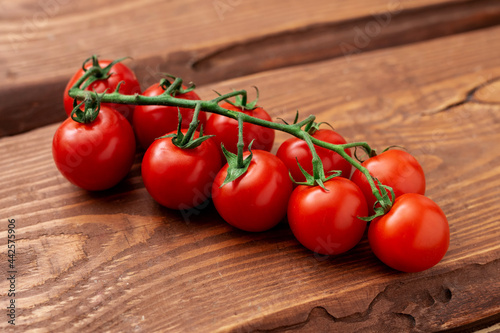 Cherry tomatoes on a wooden background. Fresh tomato branch. Vegetarian food. © Konstiantyn Zapylaie