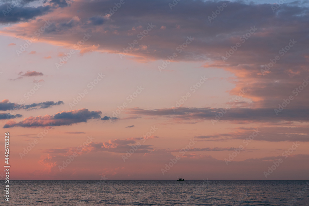 Dramatic evening sky with illuminated clouds and lonely fishing boat, sea image