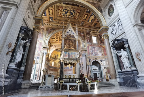 Perspective view of the apse of the Rome cathedral of San Giovanni in Laterano, with the papal altar, the inlaid ceiling and the vault with frescoes. photo