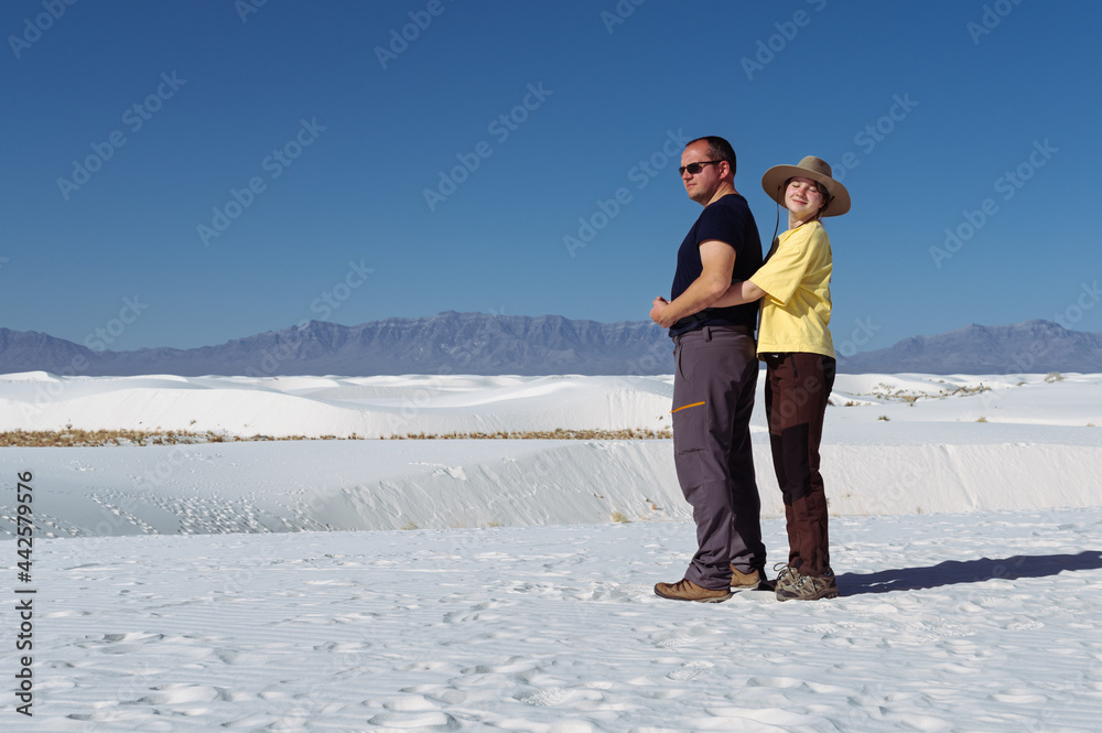 happy teenage girl hugging her dad in the dunes of white sand over the background of White Sands National park, New Mexico, in a sunny day