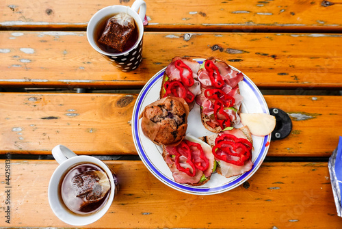 Cups of tea, a muffing and sandwiches on a table.