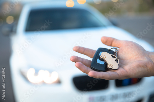 man holding car key with car